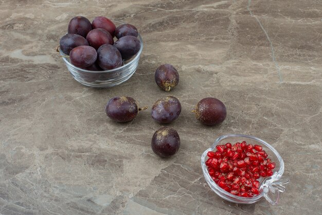大理石のテーブルに新鮮なプラムとザクロの種子。