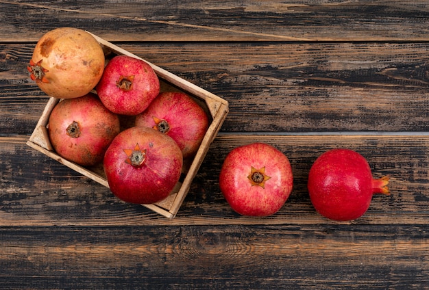 Fresh pomegranate in basket top view on wooden table