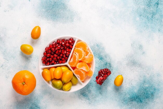 Fresh pomegranate seeds, tangerines slices and kumquat fruits.