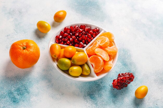 Foto gratuita semi freschi di melograno, fette di mandarini e frutti di kumquat.