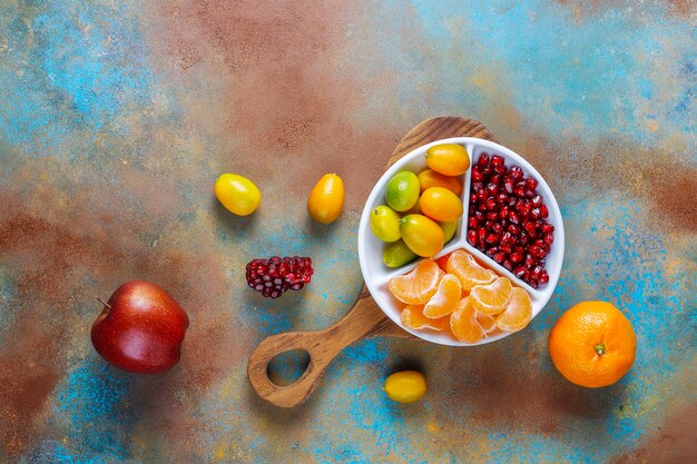 Fresh pomegranate seeds, tangerines slices and kumquat fruits.