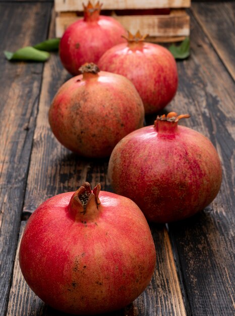 Fresh pomegranate with basket on wooden table