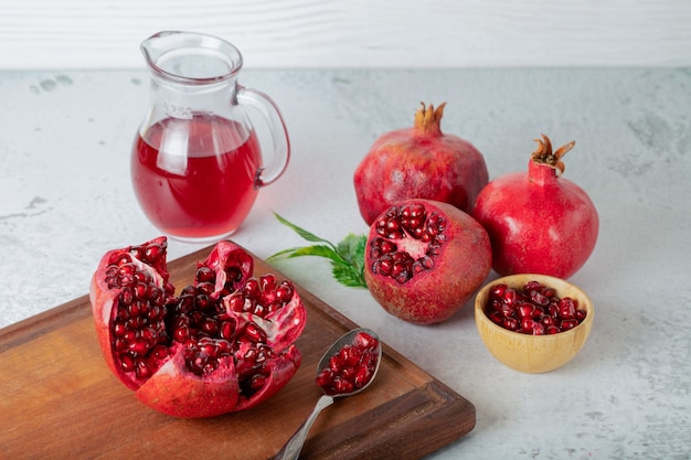 Fresh pomegranates. Whole or sliced pomegranates on wooden board over grey wall.