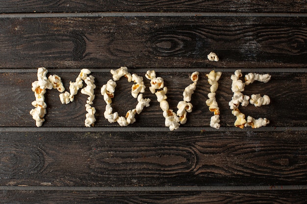 Fresh popcorn tasty salted movie word shaped on the brown rustic wooden desk