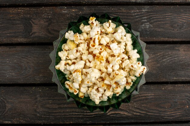 Fresh popcorn a top view inside round plate on a brown