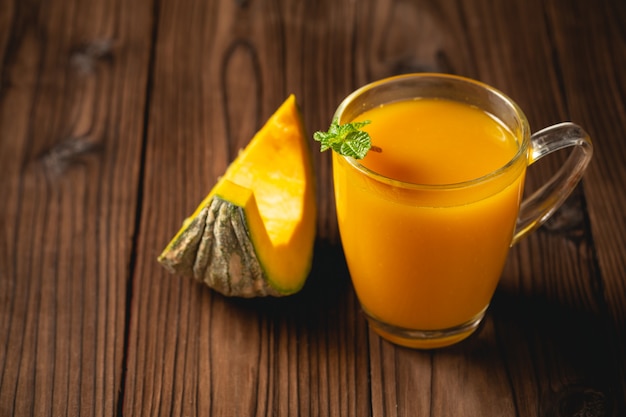 Fresh pumpkin juice in glass on wooden table.