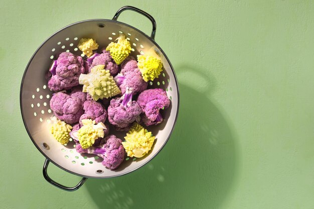Fresh purple cauliflower and green romanesco on a green background top view