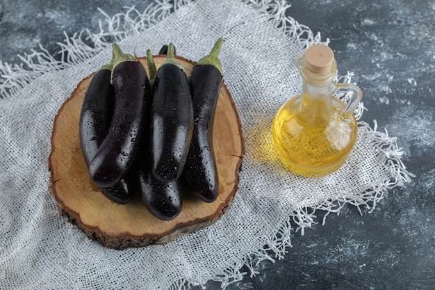 Melanzane viola fresche su tavola di legno e bottiglia di olio. vista dall'alto.