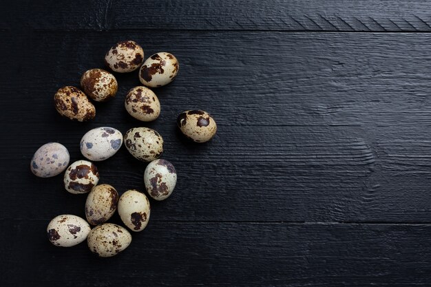 Fresh quail eggs on the dark wooden surface.