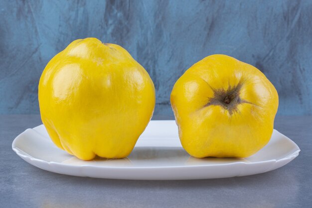 Fresh quince fruits on plate on the dark surface