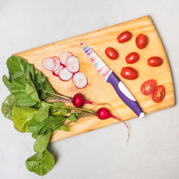Fresh radishes and tomatoes on wooden cutting board