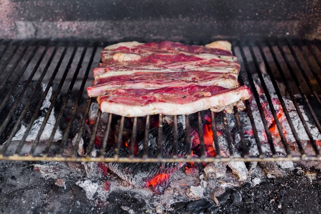 Fresh raw beef fillet on baked metal sheet over the burnt coal