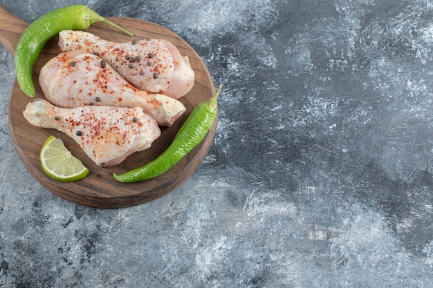 Fresh raw chicken drumsticks on wooden board.