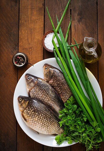 Fresh raw crucian on a wooden with herbs.