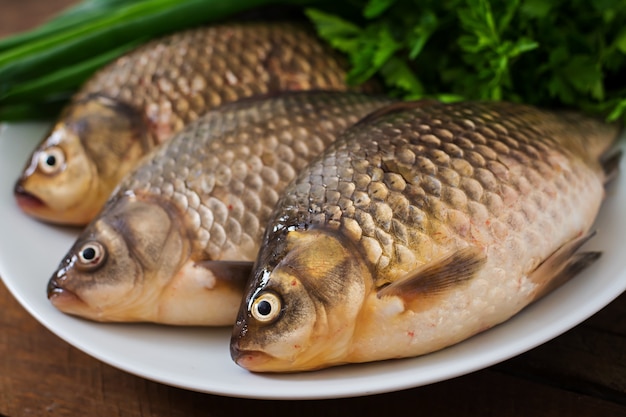 Free photo fresh raw crucian on a wooden with herbs