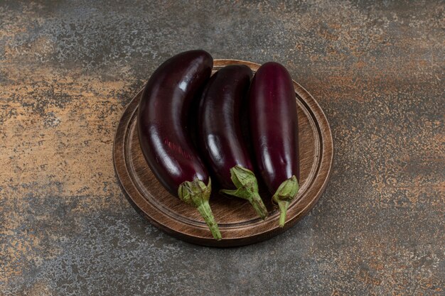 Fresh raw eggplants on the board  on the marble surface