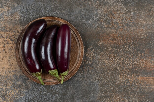 Fresh raw eggplants on the board  on the marble surface