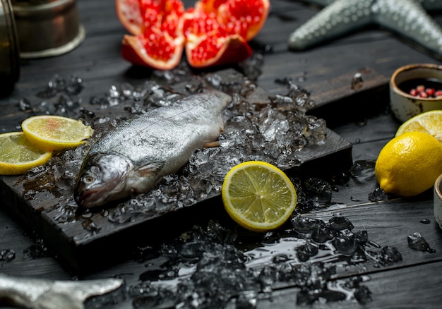 신선한 생선, 레몬, 석류 및 얼음 조각.