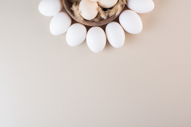 Fresh raw white chicken eggs placed on beige table .