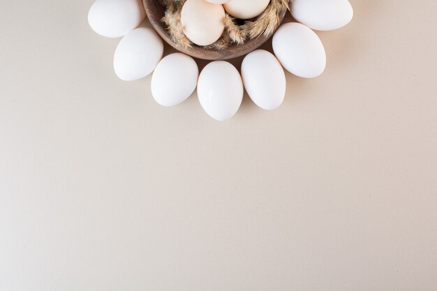 Fresh raw white chicken eggs placed on beige table .