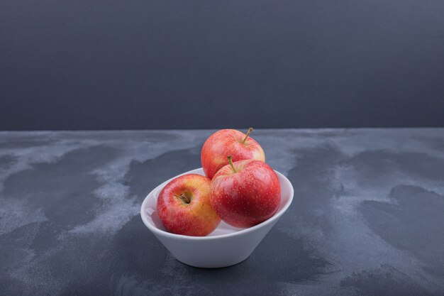 하얀 그릇에 신선한 빨간 사과입니다.