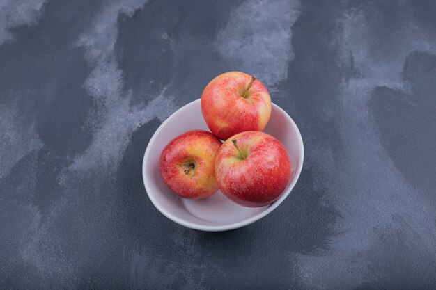 Fresh red apples in white bowl.