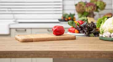 Free photo fresh red bell pepper on a wooden plank against the background of a kitchen interior.