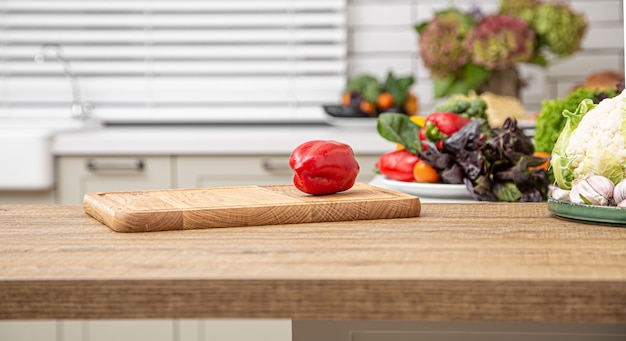Fresh red bell pepper on a wooden plank against the background of a kitchen interior.