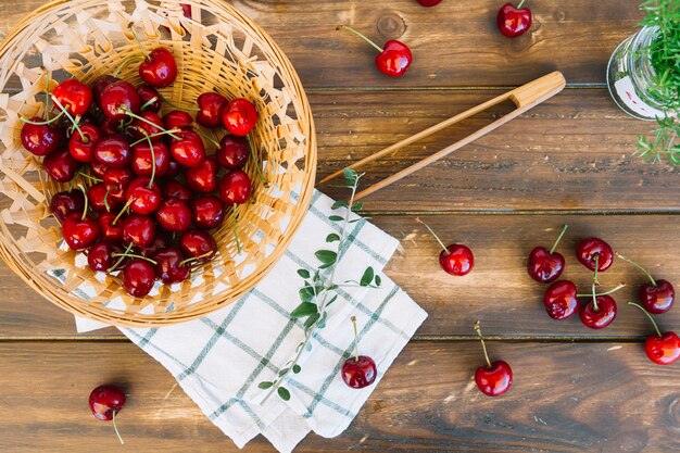 Fresh red cherries in wicker bowl on wooden background