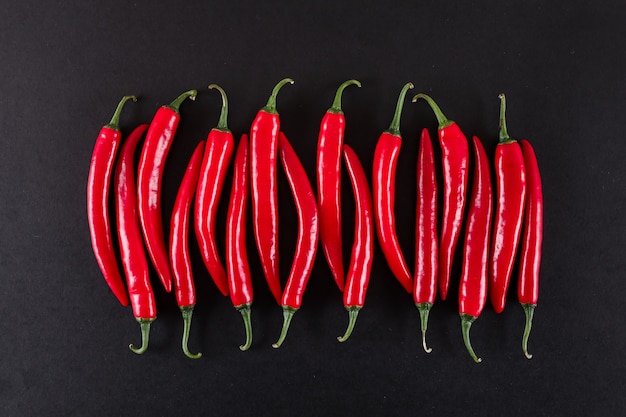fresh red chili peppers on black surface