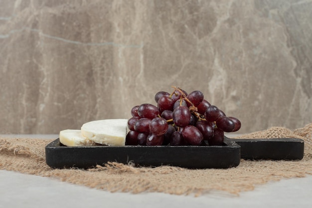 Свежий красный виноград и белый сыр на черной доске