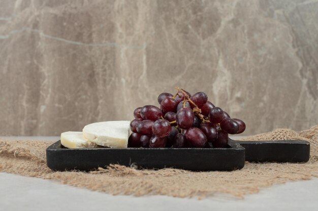 Fresh red grapes and white cheese on black board