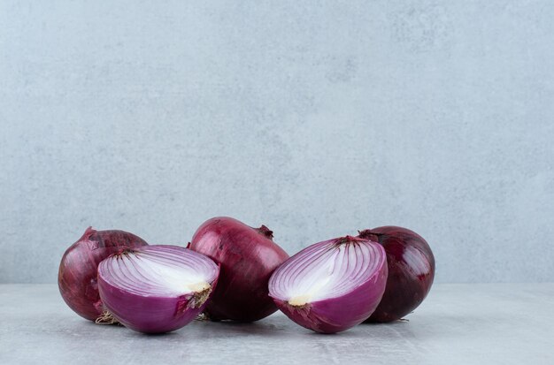 Fresh red onions on stone surface.