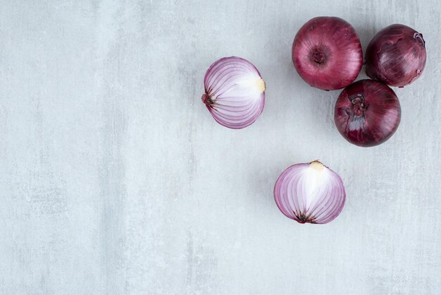 Fresh red onions on stone surface.