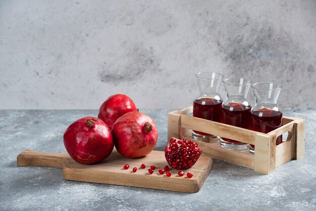 Fresh red pomegranates on wooden board with juice.