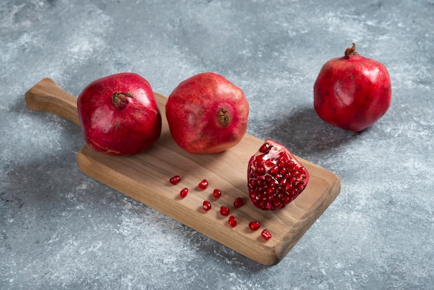 Fresh red pomegranates on wooden board.