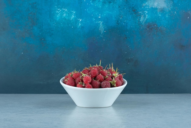 Fresh red raspberries in white bowl.