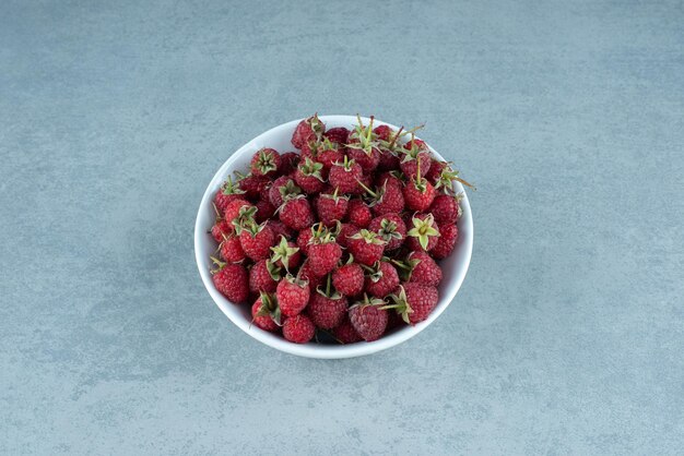 Fresh red raspberries in white bowl.