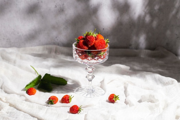 콘크리트 배경에 있는 테이블에 있는 유리잔에 신선한 빨간 딸기.
