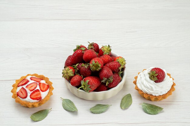 가벼운 책상에 케이크와 함께 접시 안에 신선한 빨간 딸기 부드럽고 맛있는 딸기