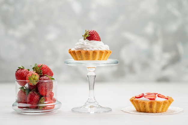 fresh red strawberries mellow and delicious berries with cakes on light desk