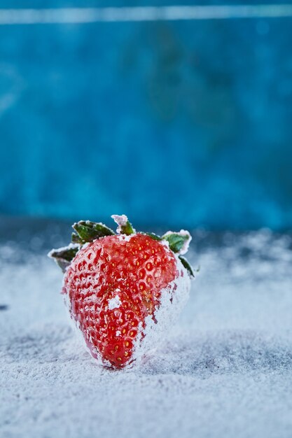 Fresh red strawberry on blue surface with powder