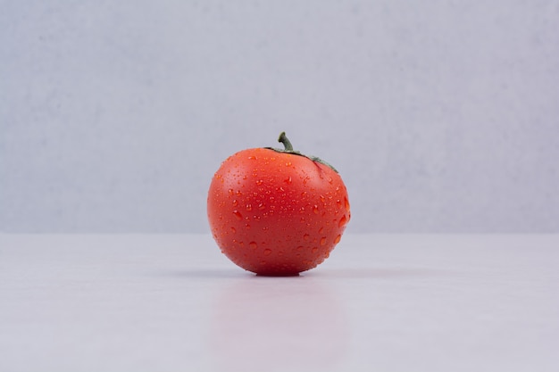 Свежий красный помидор на белой поверхности