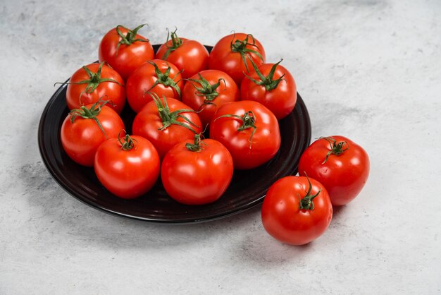 Fresh red tomatoes on a black plate.