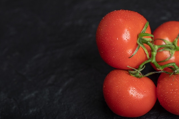 Fresh red tomatoes on dark surface