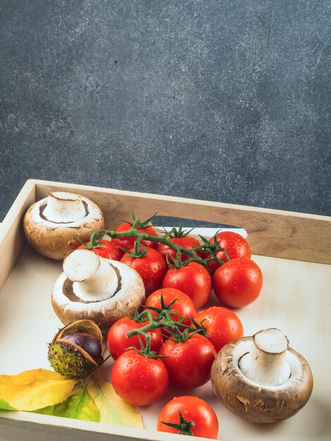 Fresh red tomatoes; mushrooms and chestnut in wooden tray