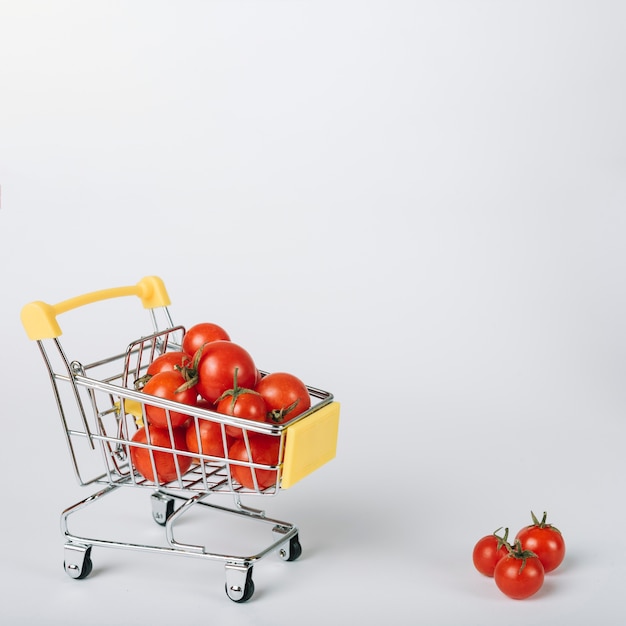 Fresh red tomatoes in trolley on white background