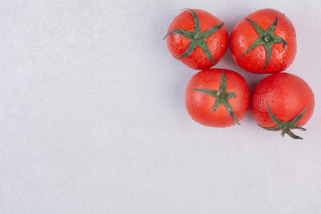 Fresh red tomatoes on white table.