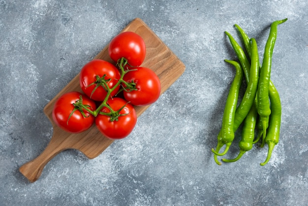 Pomodori rossi freschi sulla tavola di legno con peperoncino.