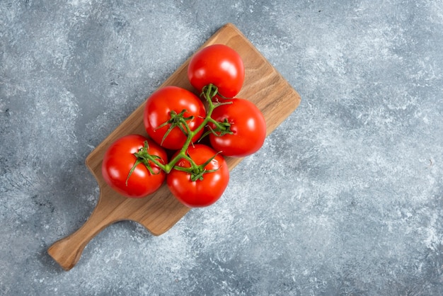 Fresh red tomatoes on wooden board.